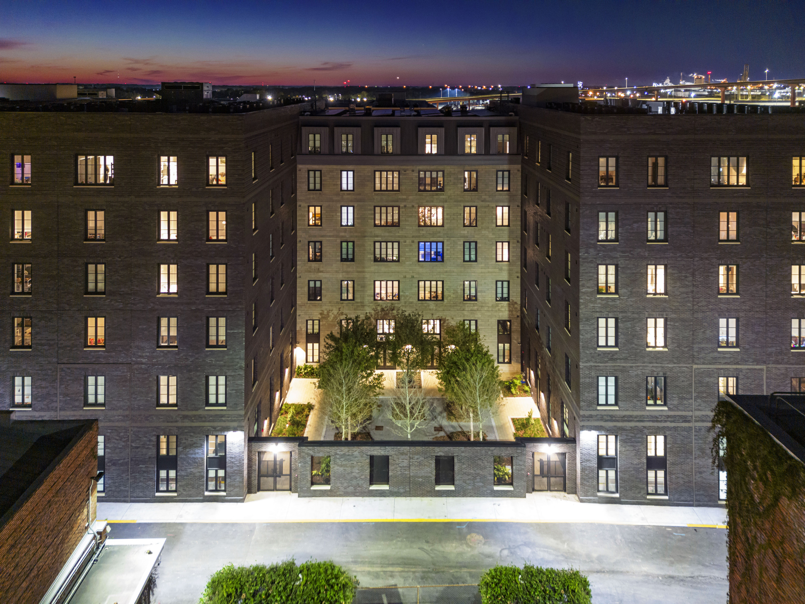 Nighttime aerial view into the landscaped central courtyard between The Ann Savannah's brick residential wings.